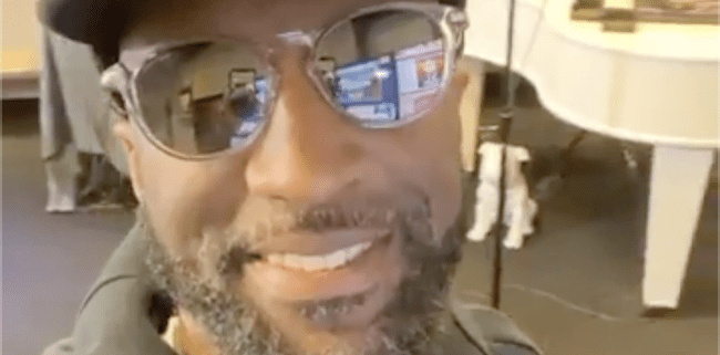 Man smiling with sunglasses and hat indoors.